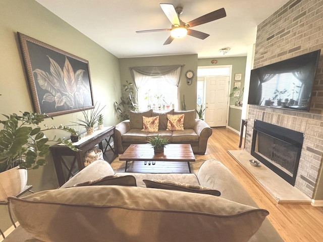 living room featuring light hardwood / wood-style flooring, a fireplace, and ceiling fan