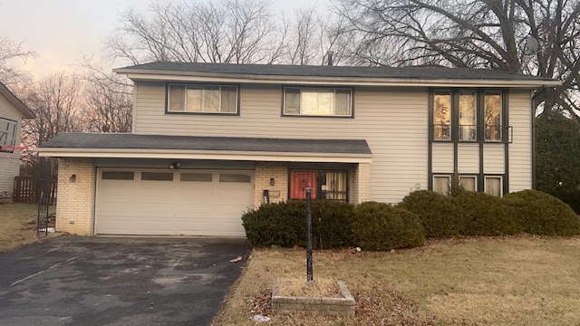 traditional-style home featuring aphalt driveway, brick siding, and an attached garage