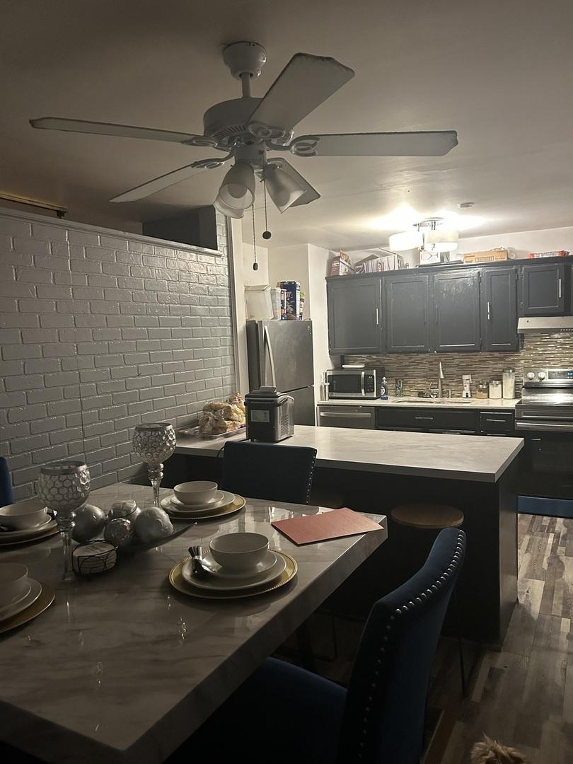 kitchen with tasteful backsplash, a kitchen breakfast bar, a center island, stainless steel appliances, and light countertops