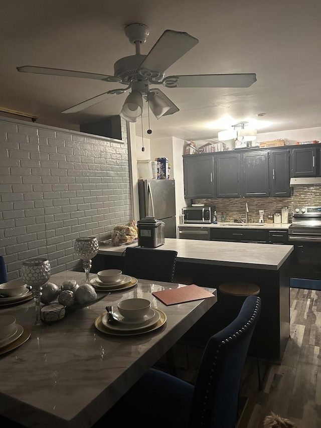 dining room featuring ceiling fan, brick wall, dark hardwood / wood-style flooring, and sink