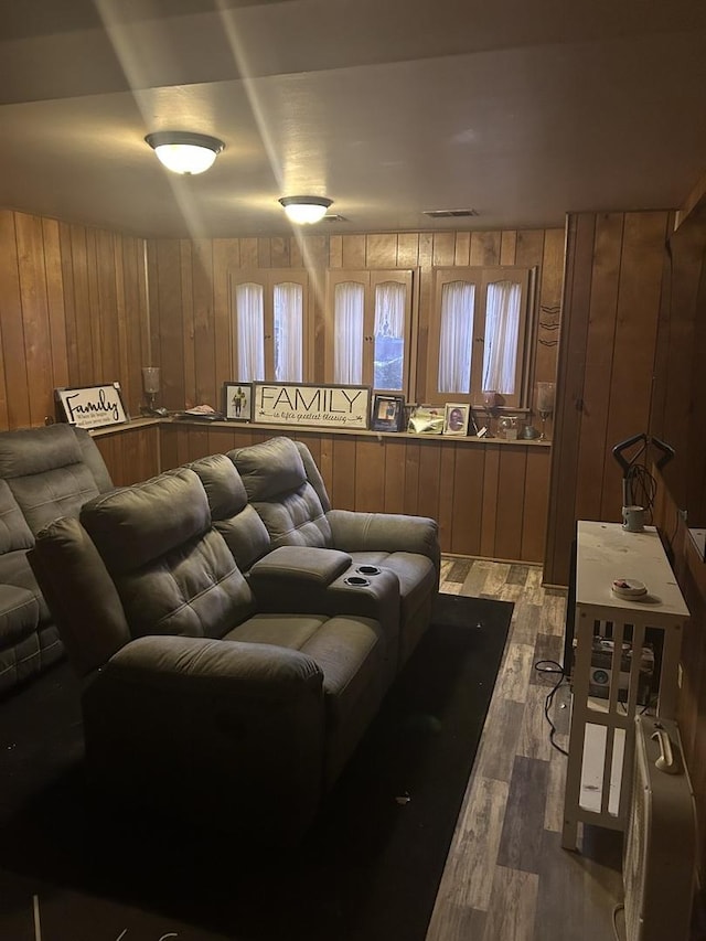 cinema room with wood walls, wood finished floors, and visible vents