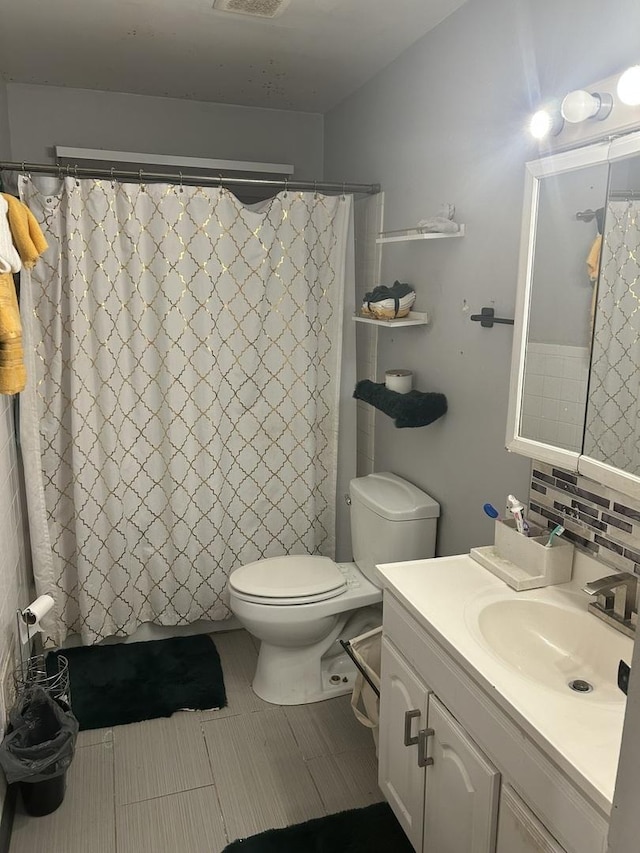 bathroom with vanity, decorative backsplash, and toilet