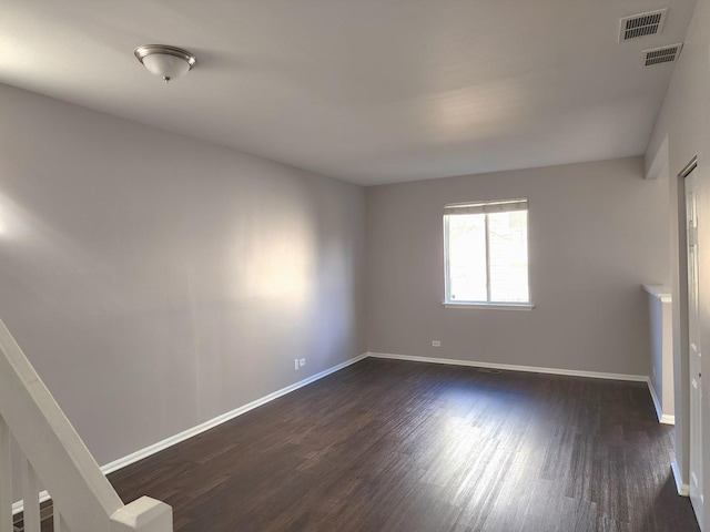 spare room with visible vents, baseboards, and dark wood-style flooring