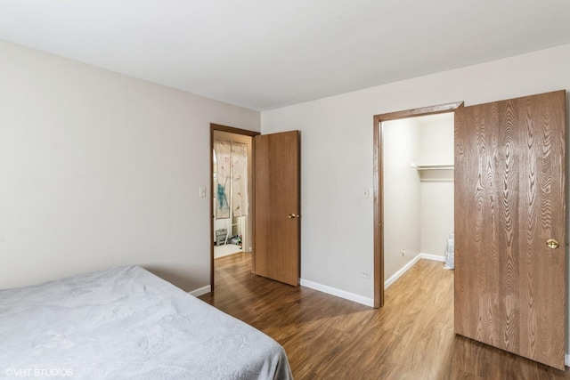 bedroom featuring a spacious closet, wood-type flooring, and a closet