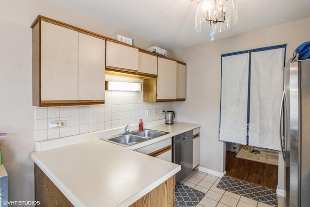 kitchen featuring sink, tasteful backsplash, decorative light fixtures, stainless steel fridge, and dishwashing machine