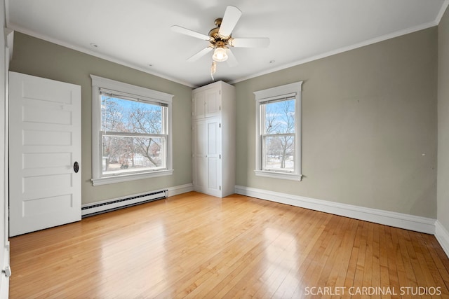 unfurnished room with a baseboard heating unit, crown molding, plenty of natural light, and light hardwood / wood-style floors