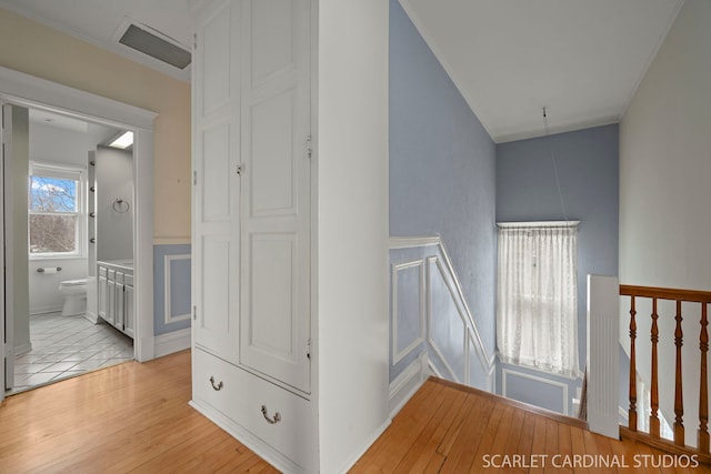 hallway with crown molding and light hardwood / wood-style floors