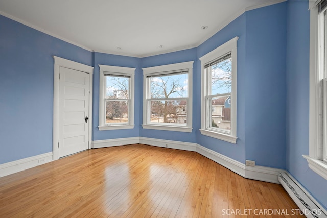 spare room with a wealth of natural light, a baseboard heating unit, hardwood / wood-style floors, and ornamental molding