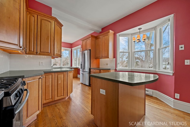 kitchen featuring stainless steel refrigerator with ice dispenser, gas range oven, hanging light fixtures, and a kitchen island