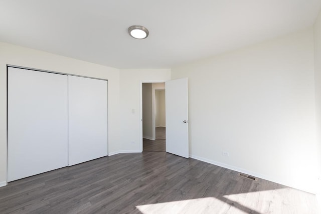 unfurnished bedroom with dark hardwood / wood-style floors and a closet