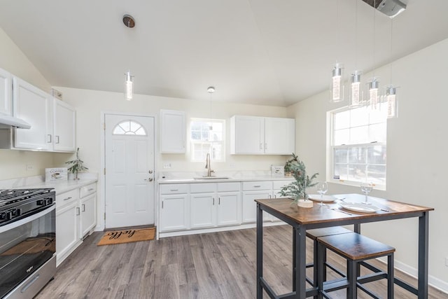 kitchen with white cabinetry, sink, vaulted ceiling, and gas stove