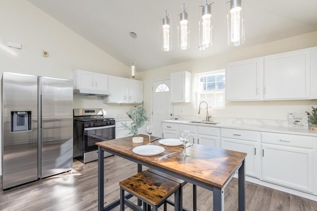 kitchen featuring sink, hardwood / wood-style flooring, white cabinetry, stainless steel appliances, and decorative light fixtures