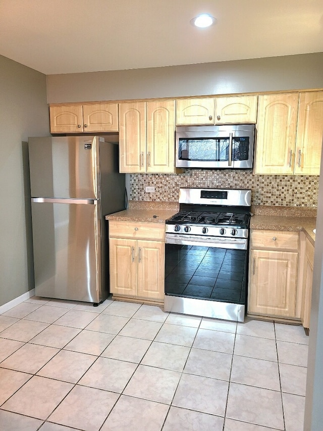 kitchen with stainless steel appliances, light brown cabinetry, decorative backsplash, and light tile patterned floors