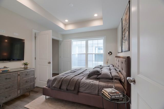 bedroom featuring a tray ceiling and light hardwood / wood-style floors