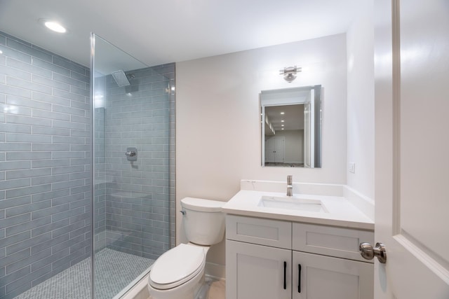 bathroom featuring vanity, a tile shower, and toilet