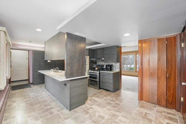 kitchen with sink, a breakfast bar, baseboard heating, tasteful backsplash, and range with two ovens