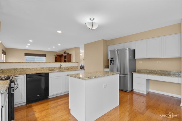 kitchen with a sink, white cabinets, light wood-style flooring, and stainless steel appliances