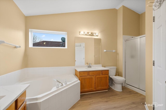 bathroom with vanity, wood finished floors, a shower stall, a garden tub, and toilet