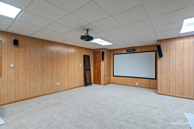 home theater room with wooden walls, baseboards, carpet, and a drop ceiling