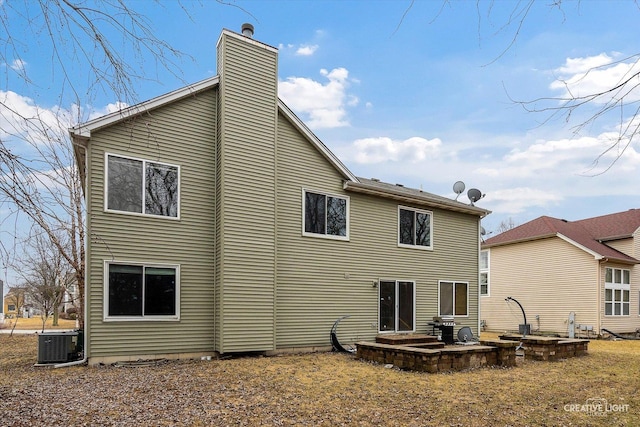 rear view of property featuring cooling unit and a chimney