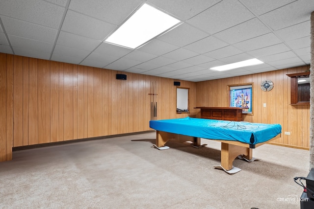 game room with a paneled ceiling, carpet, and wood walls