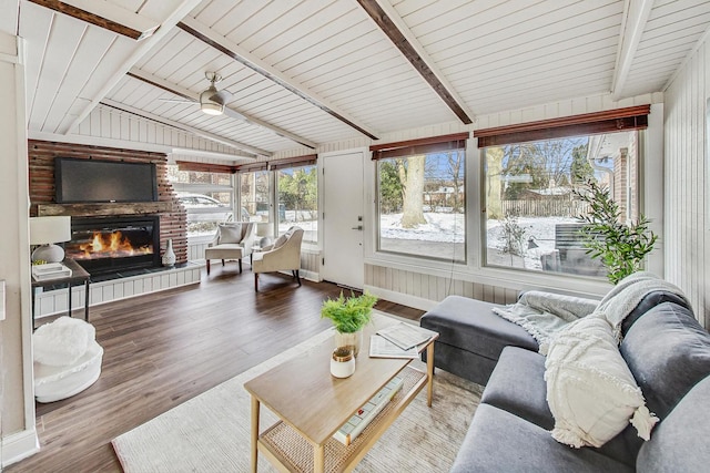 sunroom with ceiling fan, lofted ceiling with beams, and a brick fireplace