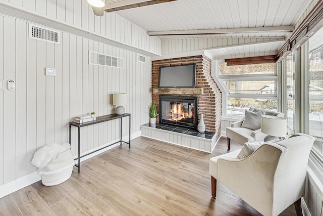 living area with beam ceiling, a wealth of natural light, and light hardwood / wood-style floors