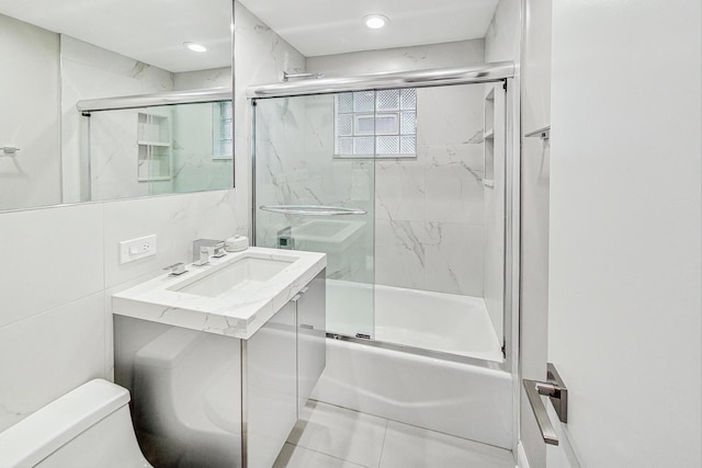 full bathroom featuring bath / shower combo with glass door, tile walls, decorative backsplash, vanity, and toilet