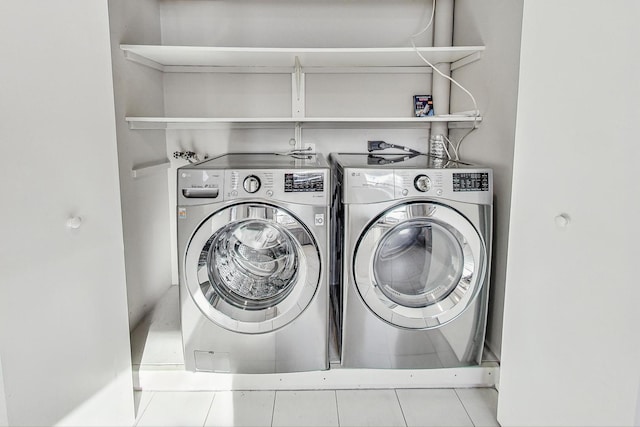 laundry room with independent washer and dryer and light tile patterned floors