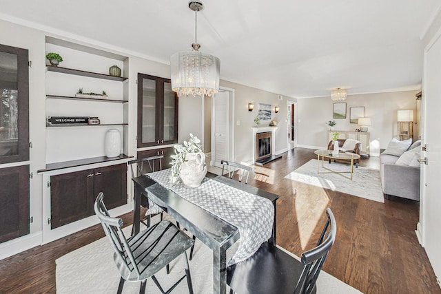 dining area with an inviting chandelier, dark hardwood / wood-style floors, built in features, and crown molding