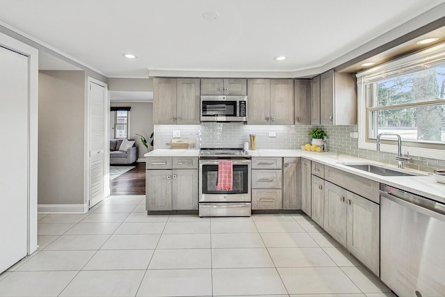 kitchen with light tile patterned flooring, stainless steel appliances, sink, and backsplash