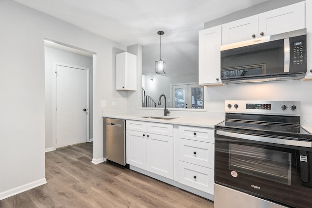 kitchen featuring appliances with stainless steel finishes, hardwood / wood-style floors, decorative light fixtures, sink, and white cabinets