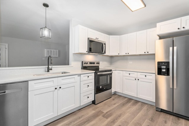 kitchen featuring white cabinetry, sink, pendant lighting, and appliances with stainless steel finishes