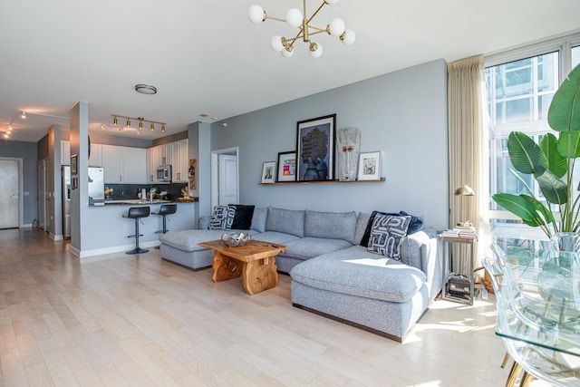 living room with rail lighting, a notable chandelier, and light wood-type flooring