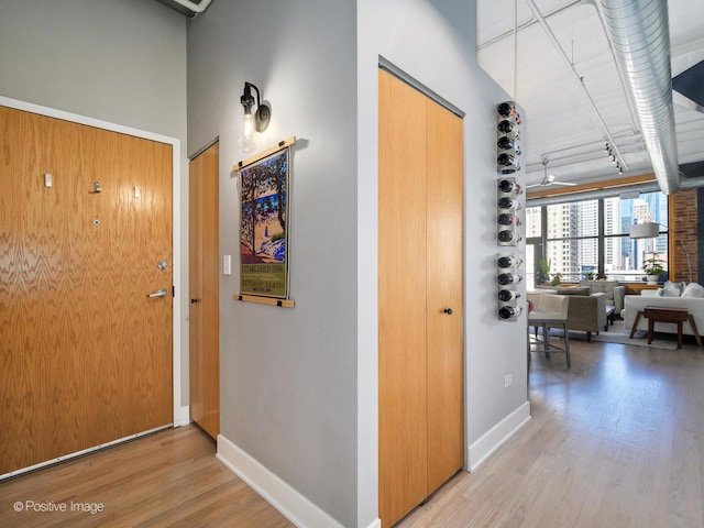 corridor featuring wood finished floors, a towering ceiling, and baseboards