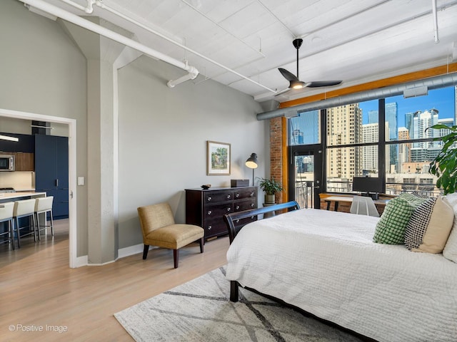 bedroom featuring a wall of windows, baseboards, and wood finished floors