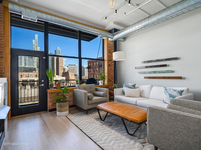 living area featuring a city view, a high ceiling, wood finished floors, expansive windows, and rail lighting