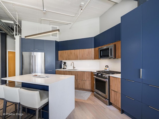 kitchen featuring a high ceiling, a sink, modern cabinets, high quality appliances, and a kitchen breakfast bar