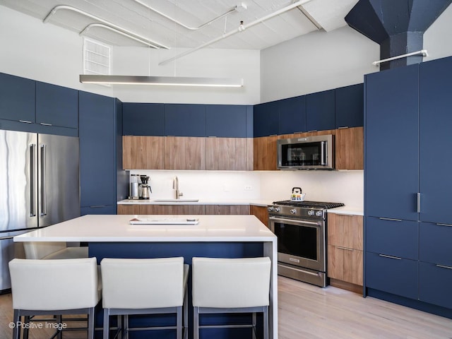 kitchen with blue cabinets, modern cabinets, appliances with stainless steel finishes, and a sink