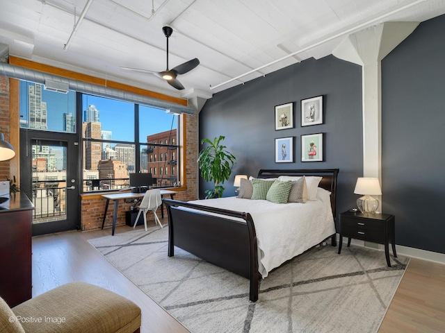 bedroom featuring brick wall, wood finished floors, a ceiling fan, and baseboards