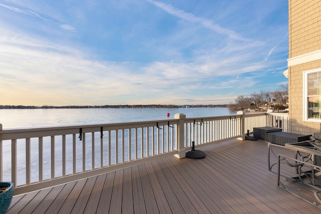 deck at dusk featuring a water view