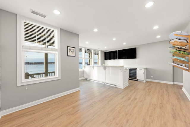 kitchen with white cabinetry, wine cooler, kitchen peninsula, a water view, and light wood-type flooring