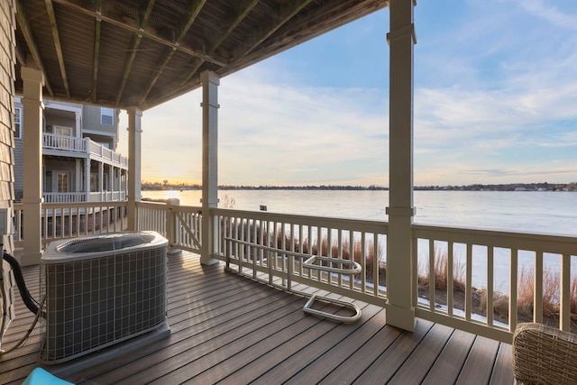 deck at dusk featuring a water view and cooling unit