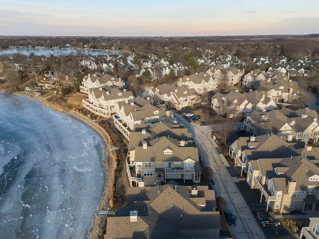 aerial view at dusk with a water view and a view of the beach