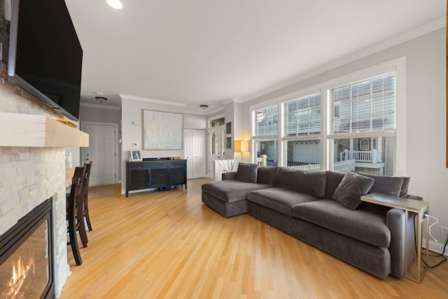 living room featuring crown molding, a fireplace, and light wood-type flooring