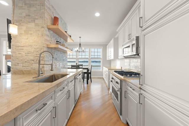 kitchen with decorative light fixtures, white cabinetry, sink, backsplash, and stainless steel appliances