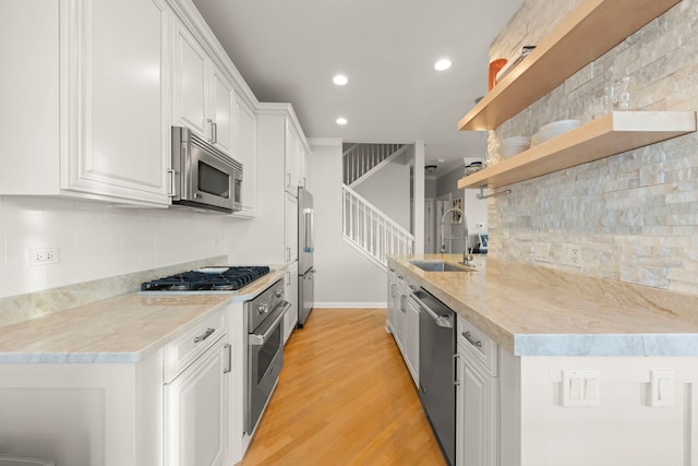 kitchen featuring sink, light hardwood / wood-style flooring, white cabinetry, backsplash, and stainless steel appliances