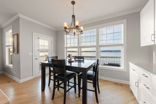 dining space featuring a water view, ornamental molding, light hardwood / wood-style floors, and a notable chandelier