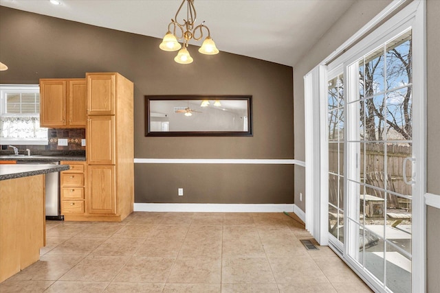 kitchen featuring light tile patterned floors, dark countertops, visible vents, vaulted ceiling, and dishwasher