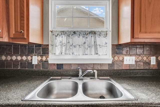 kitchen featuring tasteful backsplash, dark countertops, and a sink